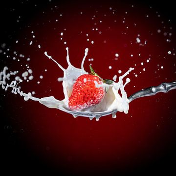 Une fraise rouge, mûre et savoureuse, tombe sur une cuillère à soupe de lait sur Photo Art Thomas Klee