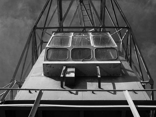 Detail van een oude industriële hijskraan met dramatische lucht in zwart-wit