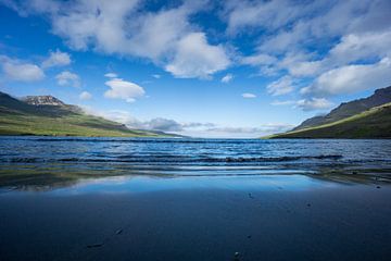 Islande - Sable réfléchissant sur une plage de sable noir entre des montagnes volcaniques vertes sur adventure-photos