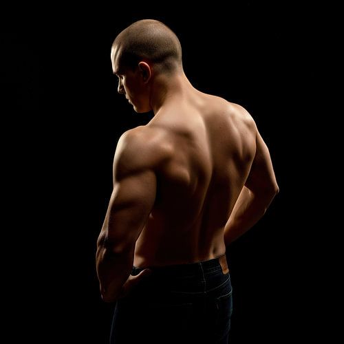 Gespierde man achteraanzicht in jeans tegen zwarte achtergrond