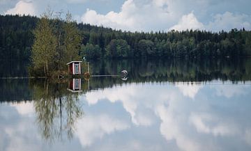 Reflectie van een Zweeds klein gebouwtje op een spiegelglad meer van Bart cocquart