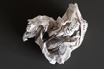 What remains of yesterday: a newspaper clump against a dark background