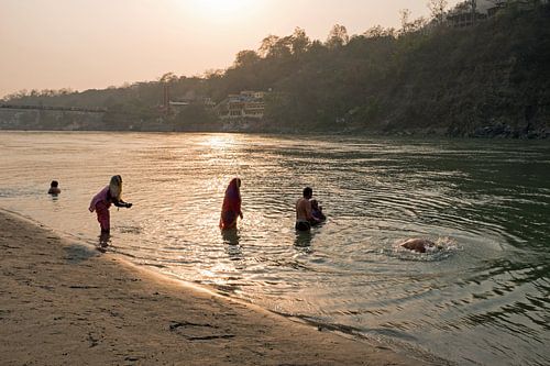 Mensen baden in de heilige rivier de Ganges in India bij zonsondergang