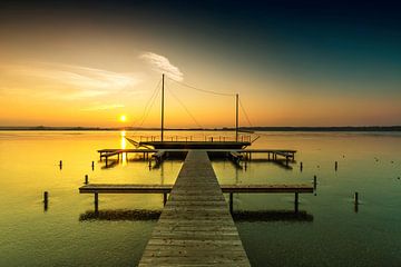 Steg mit Segelboot im Sonnenuntergang