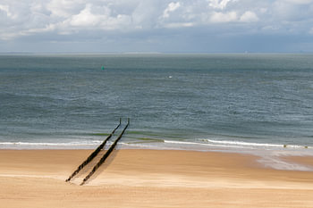 Ein menschenleerer Strand bei Zoutelande mit einer Reihe von Wellenbrechern