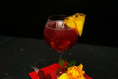 Gin cocktail met frambozen en ananas.