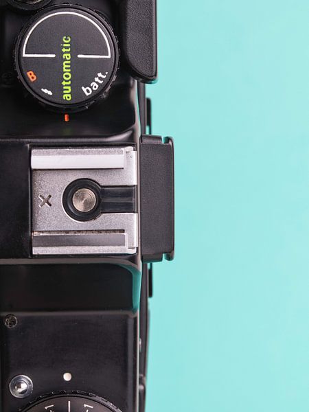 Nahaufnahme einer alten 'Praktica'-Kamera auf blau/grünem Hintergrund. von Iris Koopmans