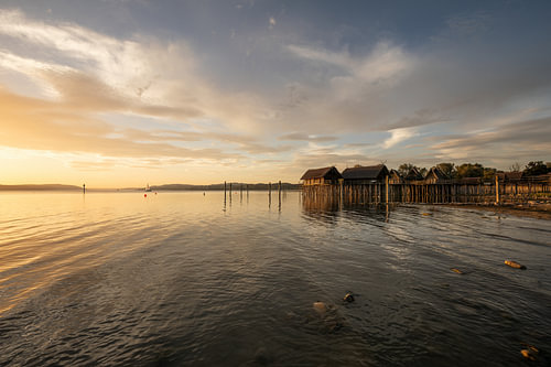 Zeilboot aan de horizon voor de paalwoningen in Unteruhldingen aan het Bodenmeer