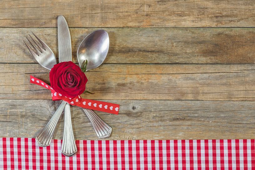 Hochzeits- oder Valentinstagstisch mit arrangiertem Silberbesteck und roter Rosenblüte von Alex Winter