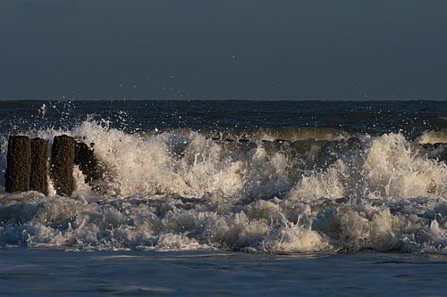 Vakantiegevoel: Golven spatten uiteen in het licht op de golfbrekers