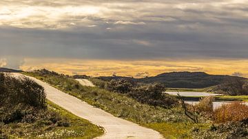 Sonne färbt bewölkte niederländische Dünenlandschaft von Luuk Kuijpers