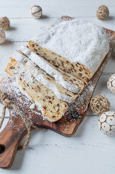 Stollen de Noël fait maison posé sur une planche rustique sur fond blanc