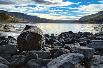 Rustig bergmeer met herfstheuvels en rotsen in het heldere water