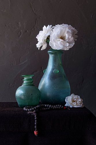 Stilleben mit weißen Rosen in grüner Vase und Rosenkranz