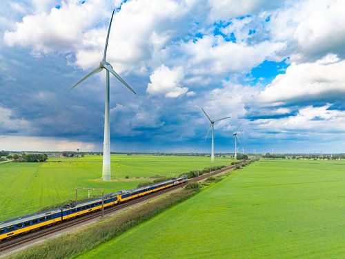 Trein van de Nederlandse Spoorwegen rijdt langs windturbines