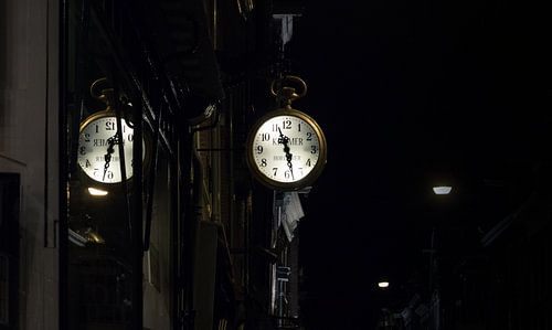 Weerspiegeling van een uurwerk in een Amsterdamse straat