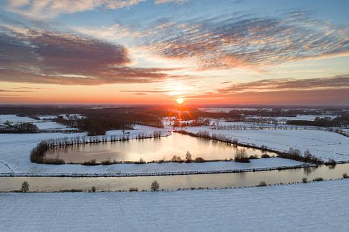 De Vecht stroomt door een besneeuwd winterlandschap tijdens zonsondergang
