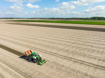Tractor plant pootaardappels in de grond tijdens de lente van Sjoerd van der Wal