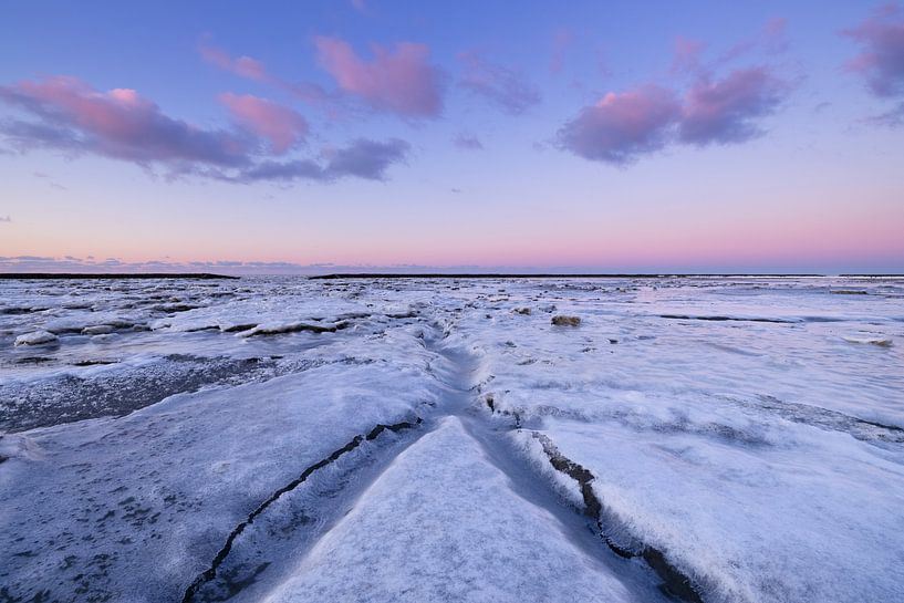 IJs bedekt de Waddenzee in de winter aan de Groningse Waddenkust tijdens zonsondergang. De ondergaan van Bas Meelker