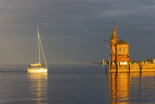 Konstanz aan het Bodenmeer, haveningang met vuurtoren, schepen, weerspiegelingen bij oranje zonsondergang