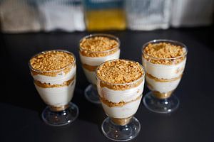 Dessert mit Joghurt, Frischkäse, Mandarinen, Keksen und Sahne in Gläsern angerichtet.