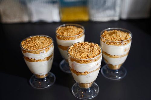 Dessert met yoghurt, roomkaas, mandarijnen, koekjes en room in glaasjes.