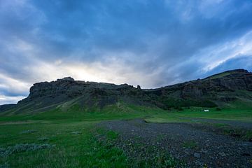 IJsland - Heldere bewolkte zonsondergang over bergen achter groene landerijen van adventure-photos