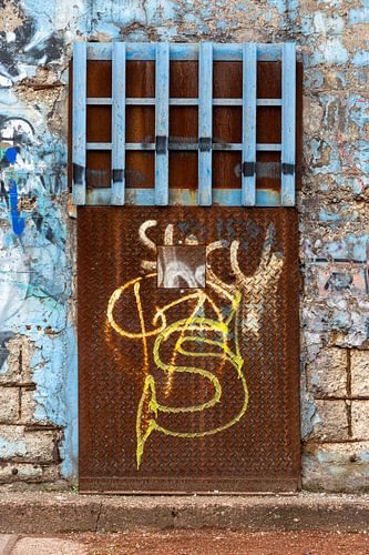 Roestig stalen loodsdeur met graffiti